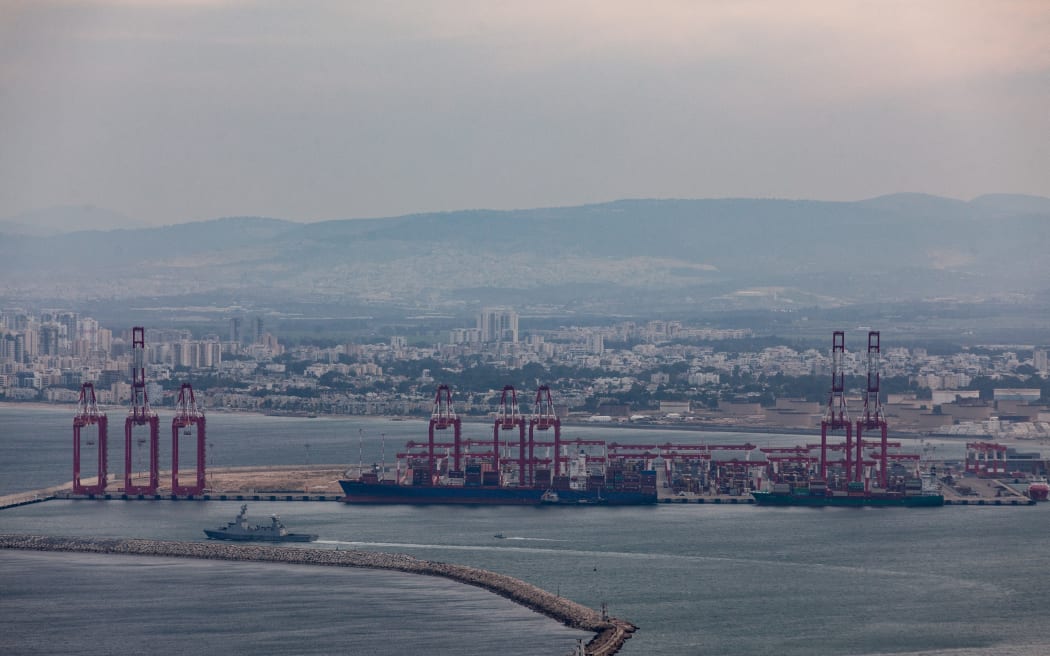 Commercial ships and an Israeli naval vessel are seen in the port city of Haifa, Israel, along the coast of the Mediterranean Sea on December 21, 2023, after the United States announced its plans to establish a multinational coalition to protect cargo ships sailing through the Red Sea from attacks by Yemen's Iran-backed Houthi group. The group claims it is targeting ships heading for Israeli ports in response to Israel's assault on the Gaza Strip. (Photo by Mati Milstein/NurPhoto) (Photo by Mati Milstein / NurPhoto / NurPhoto via AFP)