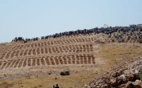 People wait by graves for the victims of the attack on a wedding party that left 54 dead in Gaziantep in southeastern Turkey.