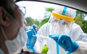 Coronavirus test - Medical worker taking a throat swab for coronavirus sample from a potentially infected elder man with the isolation gown or protective suits and surgical face masks
