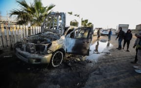 Palestinians are standing next to a vehicle in Deir Al-Balah, in the central Gaza Strip, on April 2, 2024, where employees from the World Central Kitchen (WCK), including foreigners, were killed in an Israeli airstrike, according to the NGO. The Israeli military is stating that it is conducting a thorough review at the highest levels to understand the circumstances of this ''tragic'' incident, amid the ongoing conflict between Israel and Hamas. (Photo by Yasser Qudihe / Middle East Images / Middle East Images via AFP)