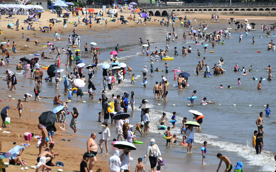 People cooling off on a beach amid hot weather in Qingdao, in China's eastern Shandong province on 1 August 2022.