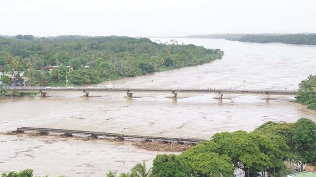 The Sigatoka river rises, with the old bridge in the foreground damaged from previous flooding.