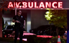 An armed police officer guards the ambulance entrance to the Central Maine Medical Center in Lewiston, Maine early on October 26, 2023 after a gunman killed at least 22 people and wounded dozens more. (Photo by Joseph Prezioso / AFP)