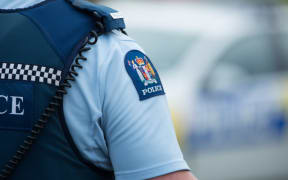 Close up of a police officer at an incident on a residential street. 6 July 2016.