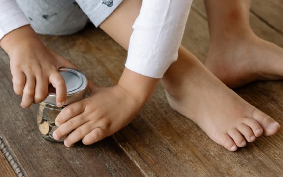 child's hands holding jar of money
