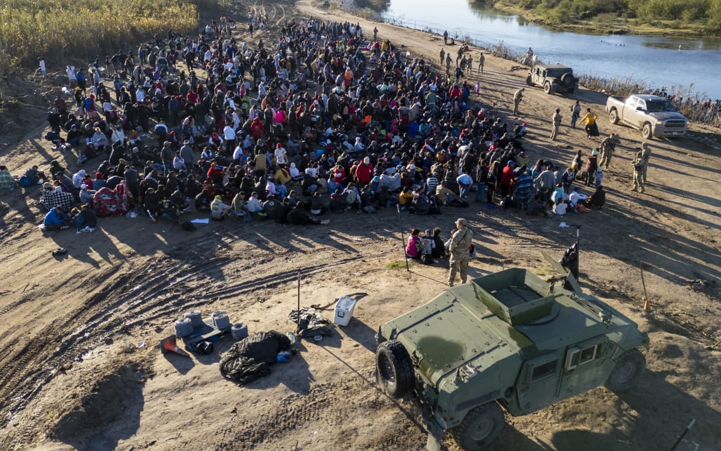 As seen from an aerial view, Texas National Guard troops watch over immigrants who crossed the Rio Grande from Mexico on 18 December, 2023 in Eagle Pass, Texas.