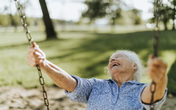 Cheerful senior woman on a swing at a playground