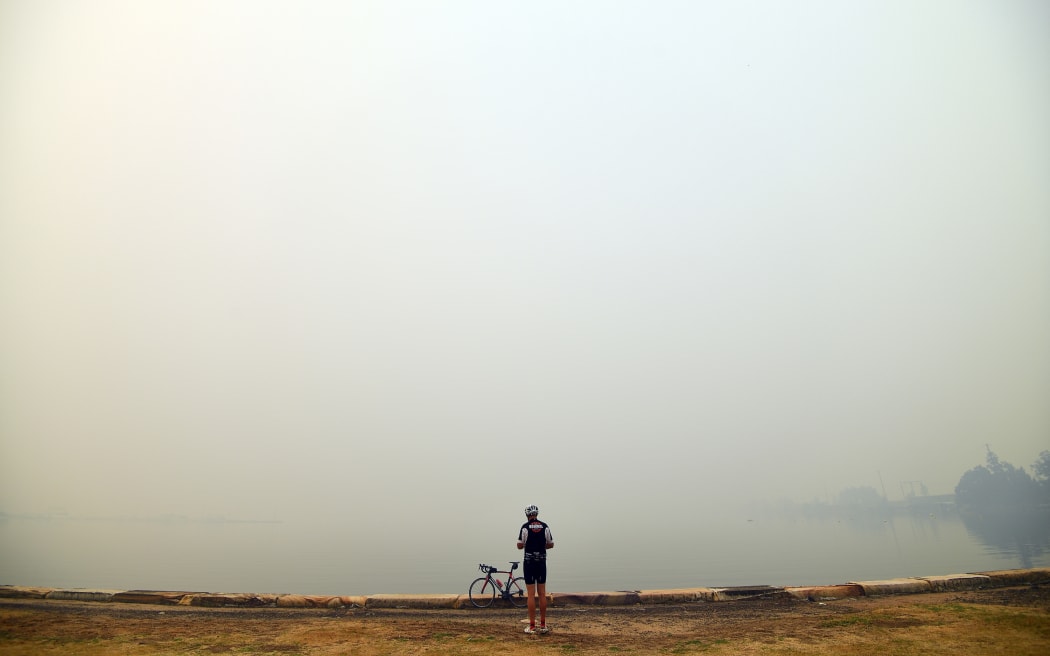 A cyclist takes pictures of smoke from bushfires in Gosford north of Sydney, on Tuesday 10 December.
