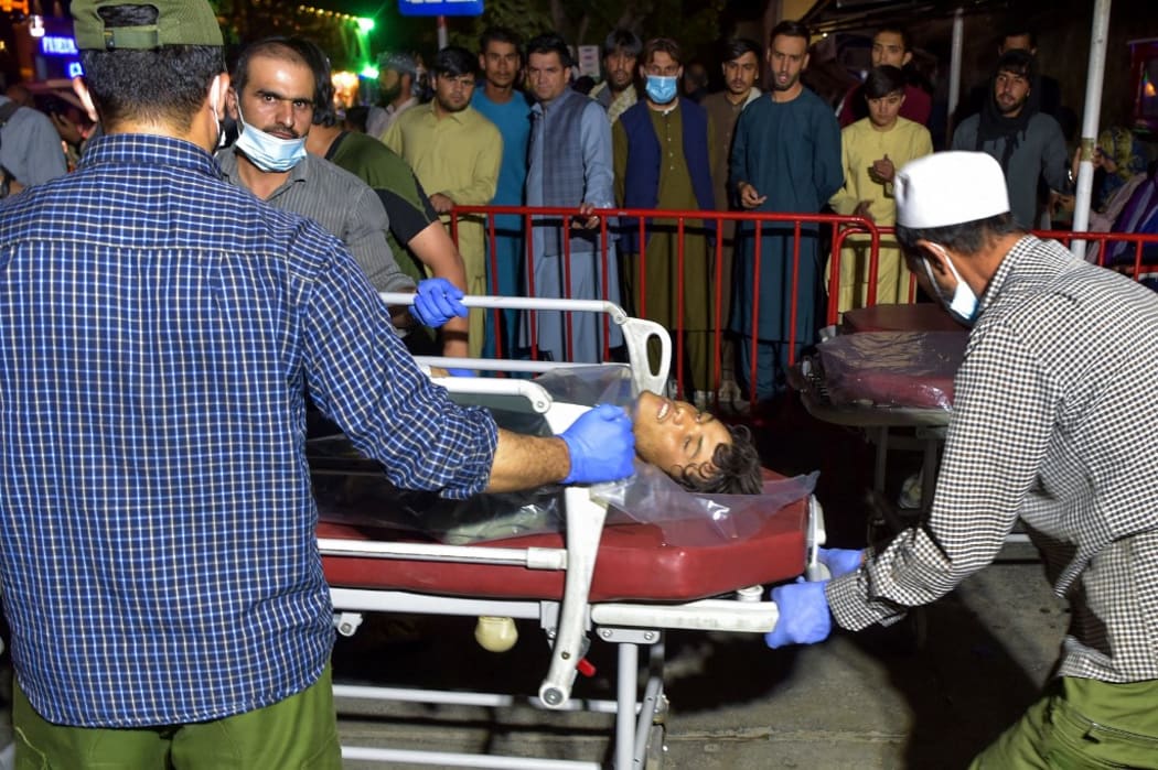 EDITORS NOTE: Graphic content / Volunteers and medical staff bring an injured man on a stretcher to a hospital for treatment after two powerful explosions, which killed at least six people, outside the airport in Kabul on August 26, 2021.