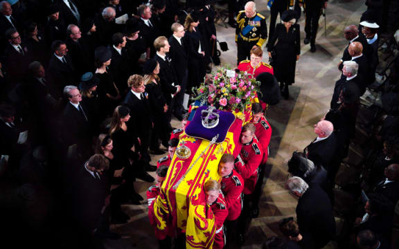 The Bearer Party of The Queen's Company, 1st Battalion Grenadier Guards carry the coffin of Queen Elizabeth II, draped in a Royal Standard and adorned with the Imperial State Crown and the Sovereign's orb and sceptre, inside St George's Chapel at Windsor Castle at the Committal Service.