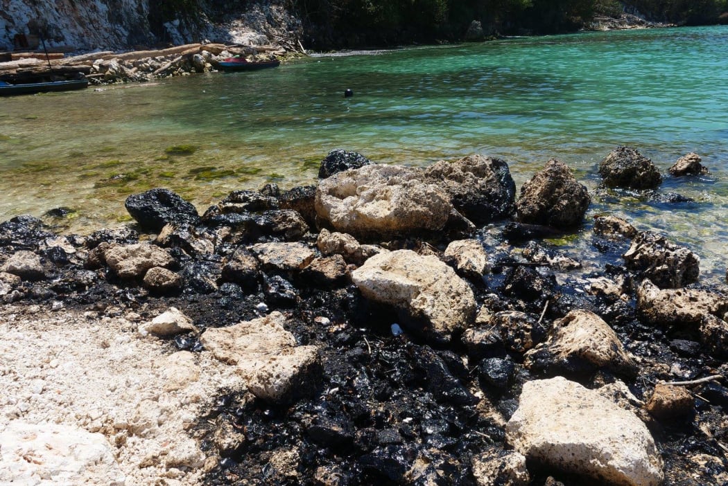 Oil blackened rocks on the seashore of Rennell Island. February 2019