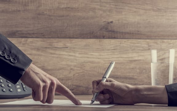 Closeup of employer showing his employee where to sign a contract, with a retro filter effect.