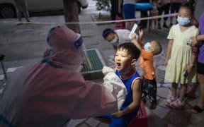 A medical worker takes a swab sample from a child for Covid-19 nucleic acid testing at a residential community in Wuhan, central China's Hubei Province,