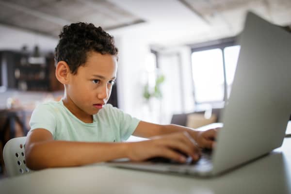 Child typing on laptop.