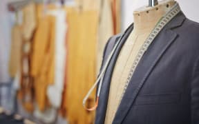 New jacket being sewn on mannequin and a measuring tape.