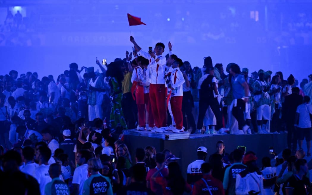 Chinese athletes take pictures from the stage as they celebrate during show of the closing ceremony of the Paris 2024 Olympic Games at the Stade de France, in Saint-Denis, in the outskirts of Paris, on August 11, 2024. (Photo by Oli SCARFF / AFP)