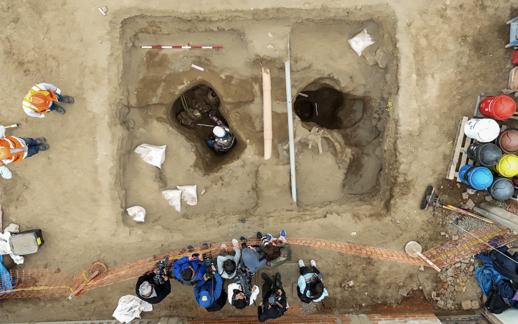 In this aerial view an archaeologist cleans a skull attributed to the pre-Inca Chancay culture accidentally unearthed by workers installing a gas pipeline in Lima's Puente Piedra district, on July 31, 2025. (Photo by Connie FRANCE / AFP)