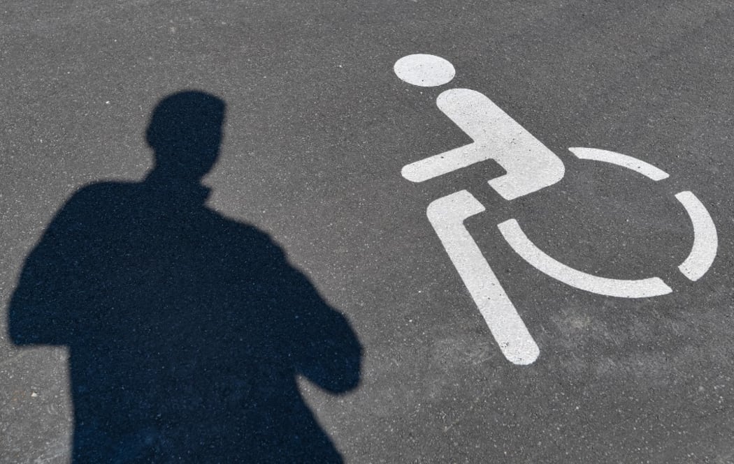 17 June 2020, Brandenburg, Ludwigsfelde: A pictogram for a disabled parking space and a shadow of a person can be seen on the asphalt.