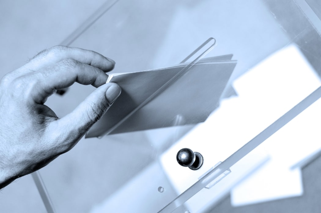 Hand putting a blank ballot inside the box, elections concept.