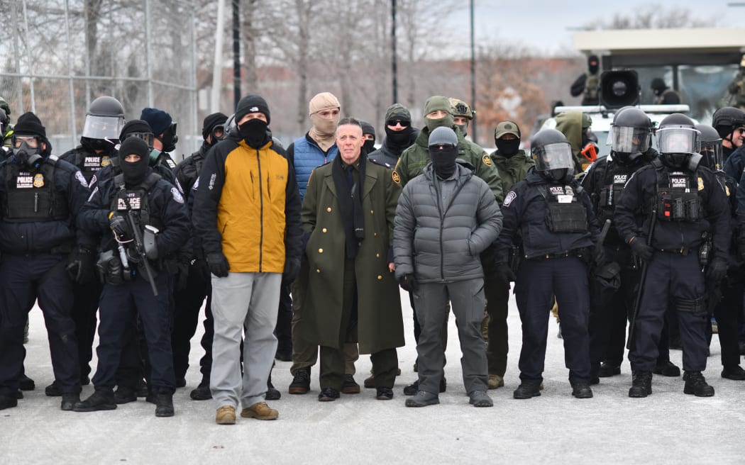 US Customs and Border Protection Commander Gregory Bovino (C) stands flanked by fellow federal agents during a protest against ICE outside the Bishop Whipple Federal Building in Minneapolis, Minnesota, on January 15, 2026. Hundreds more federal agents were heading to Minneapolis, the US homeland security chief said on January 11, brushing aside demands by the Midwestern city's Democratic leaders to leave after an immigration officer fatally shot a woman protester. In multiple TV interviews, US Homeland Secretary Kristi Noem defended the actions of the officer who shot and killed 37-year-old Renee Nicole Good, whose death has sparked renewed protests nationwide against President Donald Trump's immigration crackdown. (Photo by Octavio JONES / AFP)