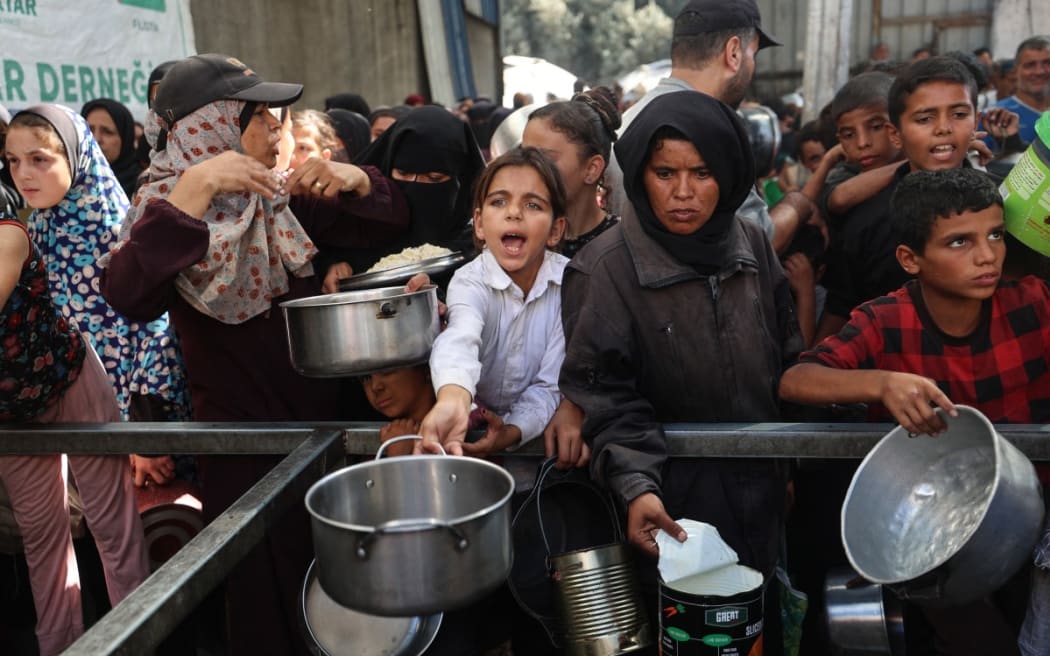 Palestinians gather to receive food portions from a charity kitchen in the Nuseirat refugee camp, located in the central Gaza Strip, on 15 October, 2025, two days after a ceasefire came into effect.