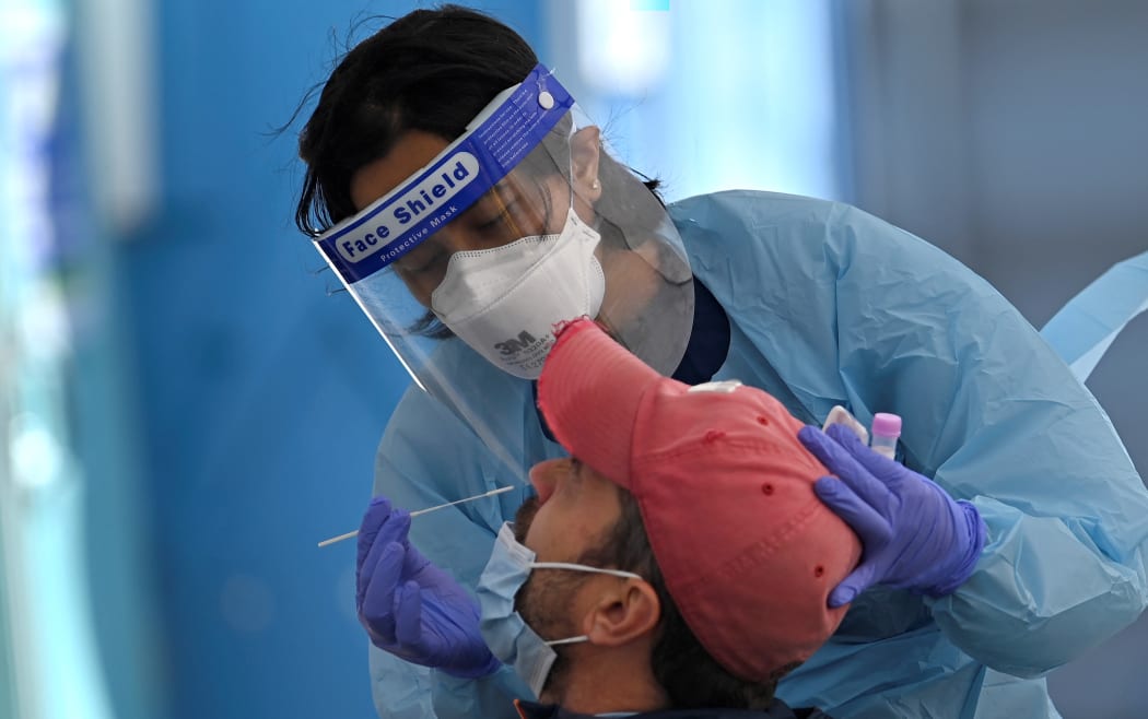 A health worker collects swab samples from a resident at a Covid-19 testing clinic in Sydney on July 17, 2021. (Photo by Steven SAPHORE / AFP)