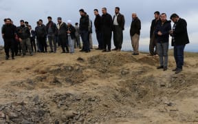 Residents look at a crater caused by a missile launched by Iran on US-led coalition forces on the outskirts of Duhok, Iraq.