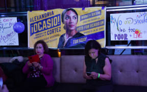 People check the latest midterm results on their phones while celebrating  at Alexandria Ocasio-Cortez's election night party in the Queens Borough of New York.