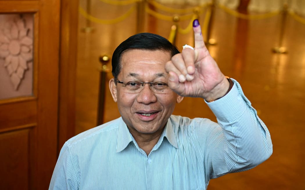 Myanmar's junta chief Min Aung Hlaing shows his inked finger after voting at a polling station during the first phase of Myanmar's general election in Naypyidaw on December 28, 2025. (Photo by Sai Aung MAIN / AFP)