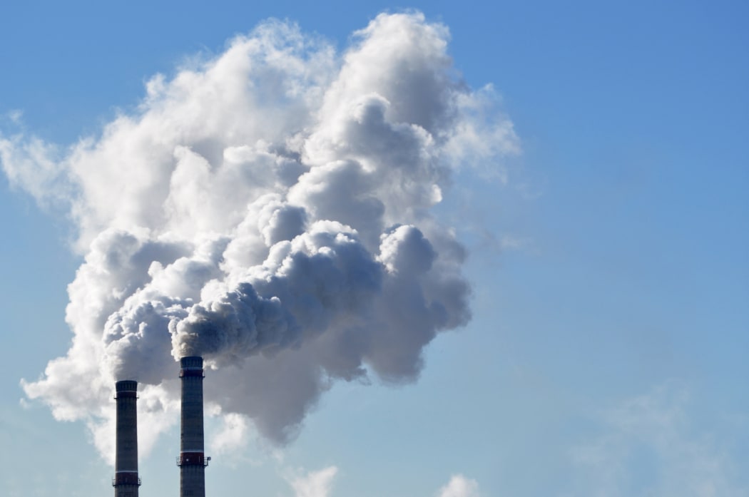 Industrial smoke from a chimney against blue sky