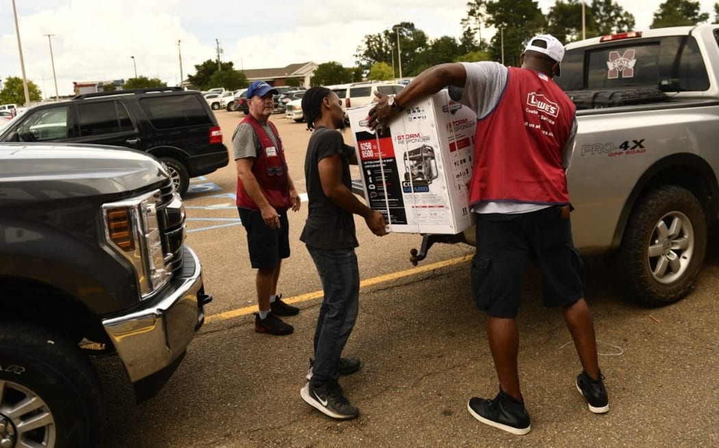 Employees of a Lowe's Home Improvement store help a customer load a generator onto a pick up truck in McComb, Mississippi, as resident prepare for Hurricane Ida on August 28, 2021.