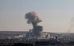 Smoke rises after a US-led coalition air strike on IS targets in Kobane in Syria (December 2014).