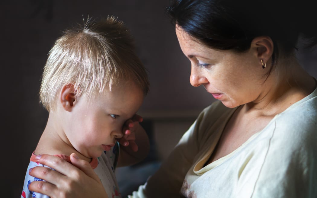 A photo of a mother comforting a small boy who looks distressed