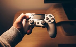Person's hand on the arrow keys of a PlayStation controller.