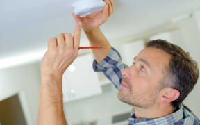 File image of man installing a smoke alarm.