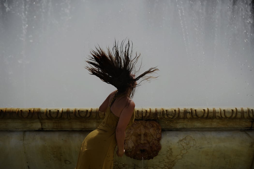 A woman refreshes herself in a fountain at Plaza de Espana, on a hot summer day in Sevilla, Spain.