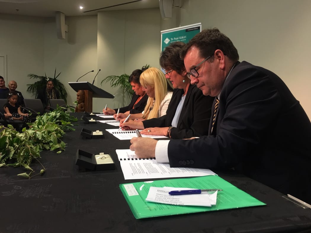 Government ministers Grant Robertson and Nanaia Mahuta, Te Puni Kōkiri chief executive Michelle Hippolite, and Parihaka rep Tina Mason sign the deal.