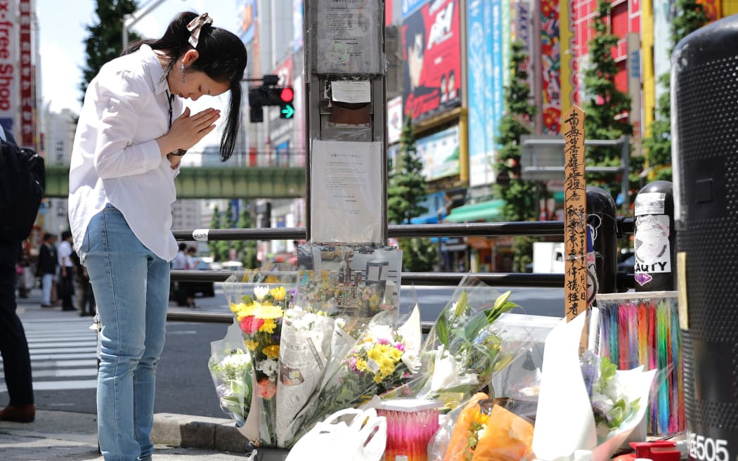 A woman prays for victims in the Akihabara district of Tokyo, ten years to the day when a man, Tomohiro Kato, drove a truck through the main intersection during a pedestrian-only day then went on a rampage with a knife on the early afternoon on June 8, 2018. Seven people died and 10 were injured in the 2008 incident. Tomohiro Kato was given the death penalty.( The Yomiuri Shimbun ) (Photo by Tetsu Joko / Yomiuri / The Yomiuri Shimbun via AFP)
