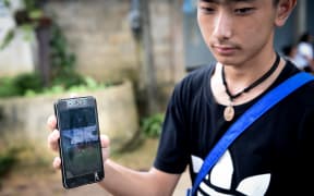 Thananchai Saengtan, 15, shows the camera a photo of his missing friends, at a football pitch near Tham Luang cave, at the Khun Nam Nang Non Forest Park in Chiang Rai province on July 1, 2018.