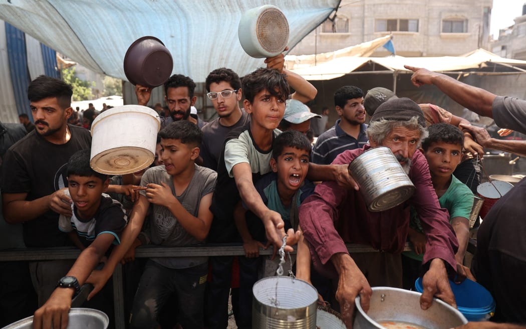 Palestinian children queue for a portion of hot food distributed by a charity kitchen at the Nuseirat refugee camp in the central Gaza Strip on July 15.