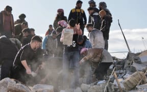 EDITORS NOTE: Graphic content / Syrian rescuers and civilians shift through the rubble of a collapsed building on February 7, 2023, in the town of Jandairis, in the rebel-held part of Aleppo province, as search and rescue operations continue following a deadly earthquake. - The death toll from the massive earthquake that struck Turkey and Syria rose above 8,300, official data showed, with rescue workers still searching for trapped survivors. (Photo by Bakr ALKASEM / AFP)