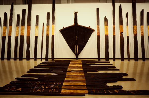 Burnt logs arranged on the floor and against a wall.