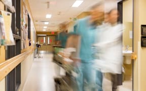 Health professionals in a hospital pulling a stretcher.