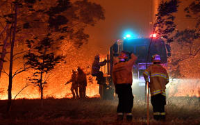 Firefighters hose down trees as they battle against bushfires around the town of Nowra in the Australian state of New South Wales on December 31, 2019.
