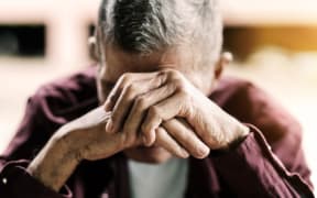 senior man covering his face with his hands.vintage tone