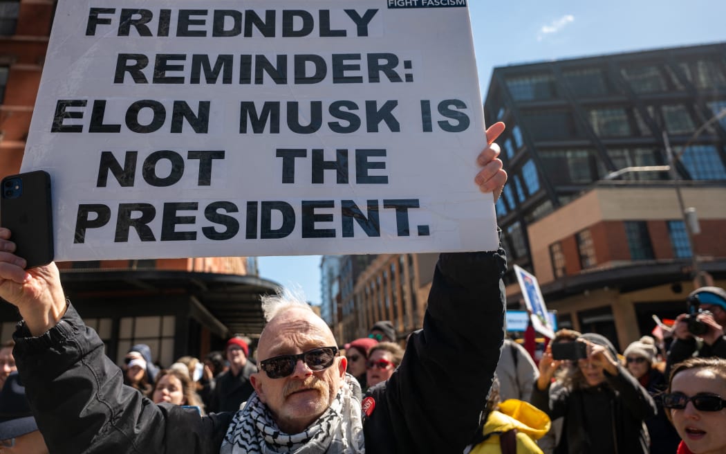 Protesters gather outside of a Manhattan Tesla dealership to demonstrate against Tesla CEO Elon Musk.