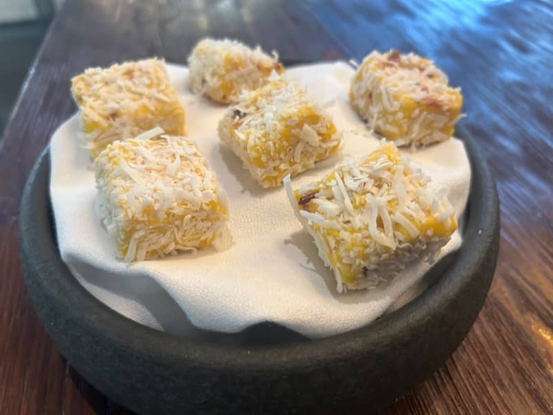 A dish of mango burfi, covered in desiccated coconut.