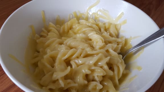 A bowl of pasta with grated cheese on top.