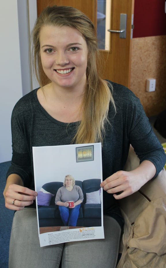 A photo of Brooke Gray with one of the images from her herstory photography project