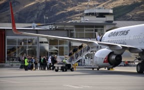 Passengers board commercial jet at Queenstown Airport.